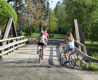 Kuva sillalla pyörillä ajavista lapsista